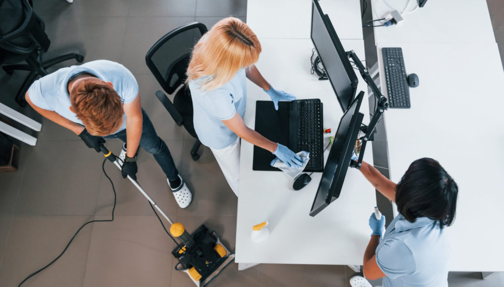 Top view. Group of workers clean modern office together at daytime Top view. Group of workers clean modern office together at daytime.